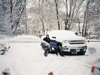 man clearing heavy snow in winter in his driveway with a snowblower