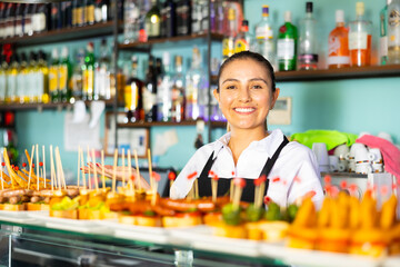 Cheerful female bartender offering delectable sandwiches pinchos in bar