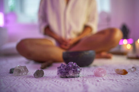 Woman practicing yoga with singing bowl and gemstones
