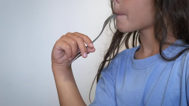 Empty fork and starving period. An alone hungry child lick the empty fock in the kitchen. A concept of starving period and food inflation in the world.