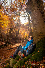 Fototapeta premium Young woman enjoying the fall colors among beech trees in October.