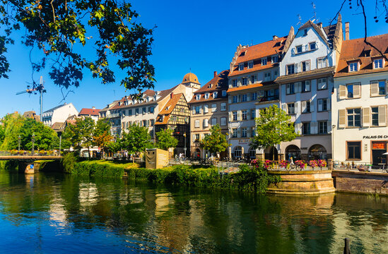 STRASBOURG, FRANCE - AUGUST 3, 2022: Scenic view of Strasbourg cityscape on sunny summer day overlooking typical timber-framed townhouses on waterfront along Ill river