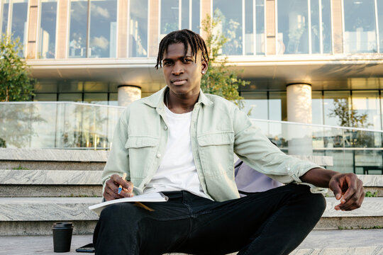 Portrait of student sitting on steps of university building