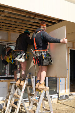 Carpenters fixing cladding board to ro
