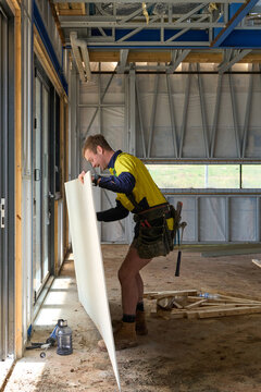 Construction worker at worksite lifting cladding board
