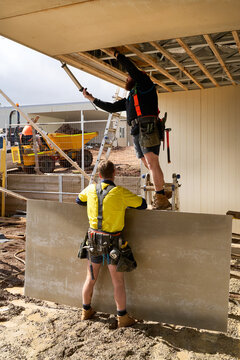 Carpenters fixing cladding to roof