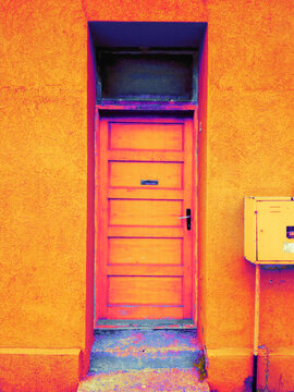 Wooden rusty front door on the old empty house in orange.