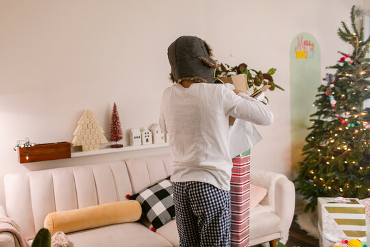 Teen boy open big box gift on Christmas by tree