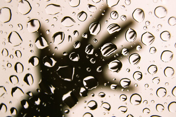 Water droplets refracting the image of a hand on the moon roof lass of  a car.