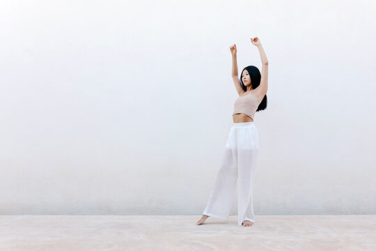 Asian dancer making step with raised arms
