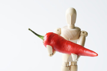 Wooden anthropomorphic mannequin with red pepper in his hands. copyspace. White background....
