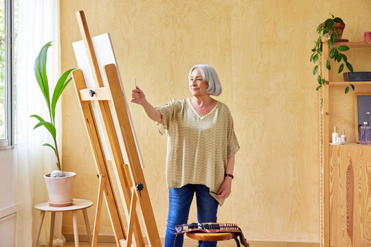 Elderly female artist measuring proportions of drawing