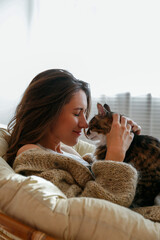 Portrait of young woman holding cute norwegian cat with green eyes. Female hugging her cute long...