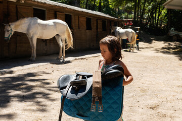 young equestrian carrying a saddle