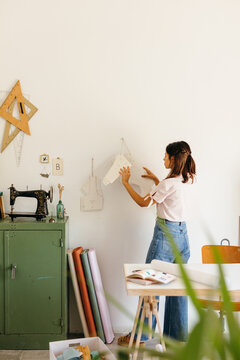 Fashion designer checks some patterns hanging on the wall.