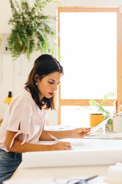 side view of a fashion designer drawing on a paper