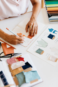 A fashion designer draws sketches in her notebook