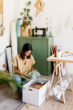 A dressmaker, choosing fabrics from a box