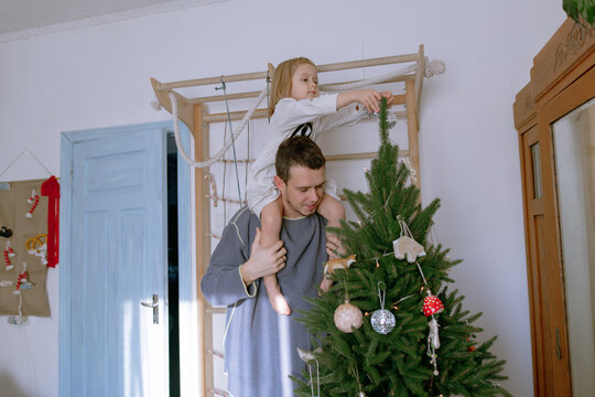 man and daughter decorating a Christmas tree