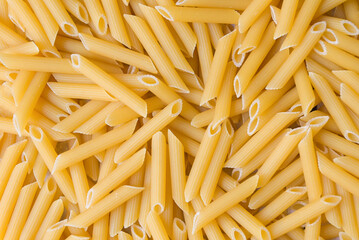 Penne pasta background - top view, raw penne pasta texture background, close up raw penne rigate pasta uncooked delicious pasta for cooking food