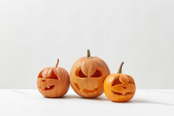 Carved Halloween pumpkins on white marble table.