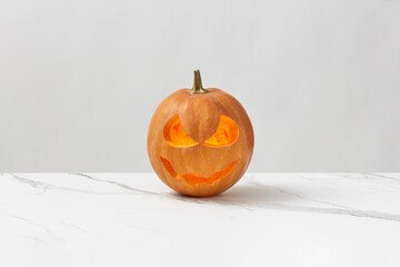 Glowing pumpkin jack-o-lantern on marble table.
