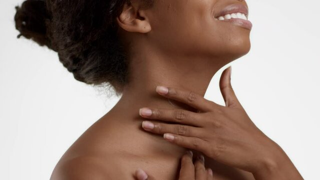 Close up shot of unrecognizable african american lady applying skin lifting cream on neck and smiling, slow motion
