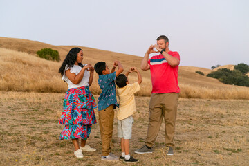 Mixed family making heart shapes with hands at field