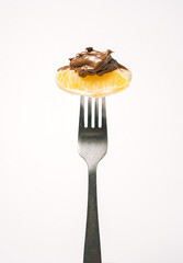 silver fork with tasteful orange slice and cocoa cream on bright white background. minimal creative...