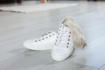 Sneakers with dirty socks on white wooden floor indoors