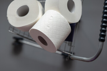 Toilet paper rolls in a supermarket trolley on a gray background.Cleanliness and health.toilet...