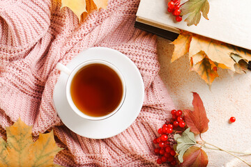 Flat lay composition with cup of aromatic tea and soft pink sweater on beige textured table. Autumn atmosphere