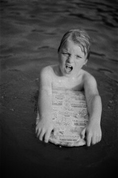 A funny boy swimming with a surf board 