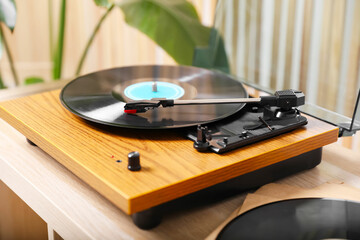 Stylish turntable with vinyl disc on light wooden table indoors