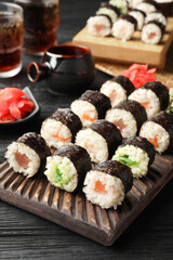 Tasty sushi rolls served on black wooden table
