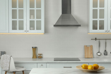 Elegant kitchen interior with modern range hood over cooktop and stylish furniture