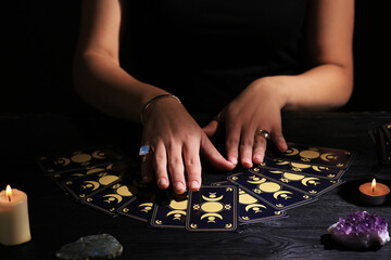 Soothsayer predicting future with tarot cards at table in darkness, closeup