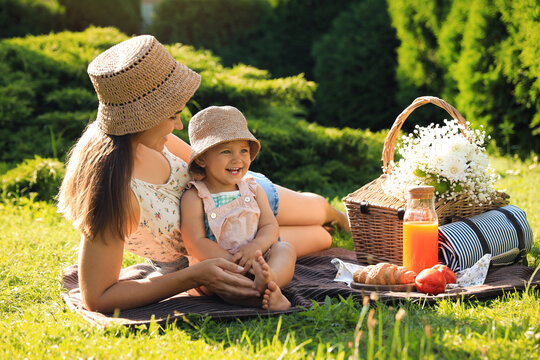 Mother with her baby daughter having picnic in garden on sunny day