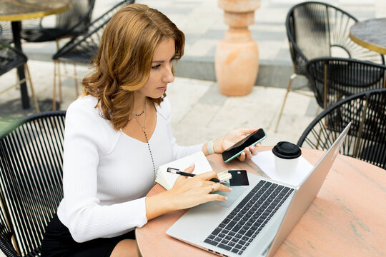 Woman working on laptop on cafe terrace