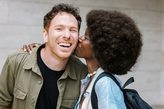 Cheerful multiethnic couple kissing at university