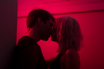 Lovers silhouettes kissing with red neon light