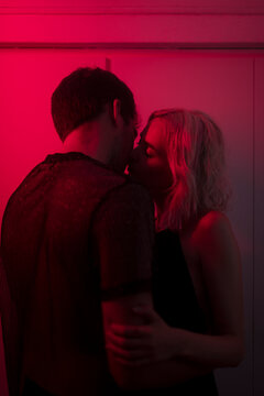 Intimate portrait of kissing couple under red light