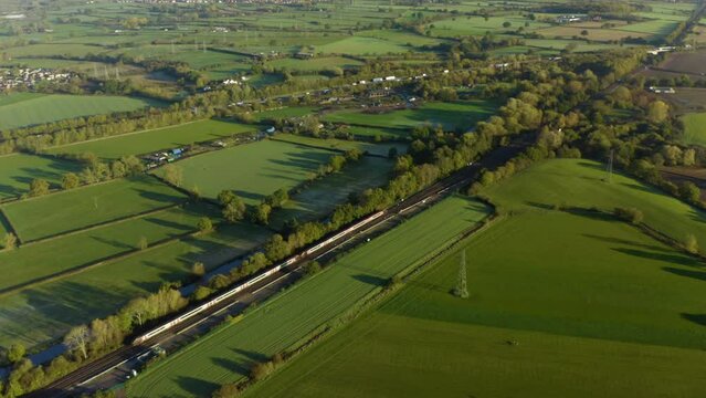 passenger train passing through countryside. Modern high speed train. High speed passenger railway train South of England, UK. Fast train aerial shot. AERIAL: High speed train train.