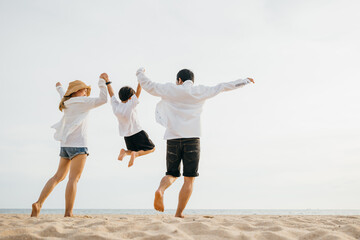 Family outdoor activities, Back family mother, father and son holding hands and jumping in air at dawn time, Happy Asian family people have fun together on beach on holiday summer vacation travel © sorapop