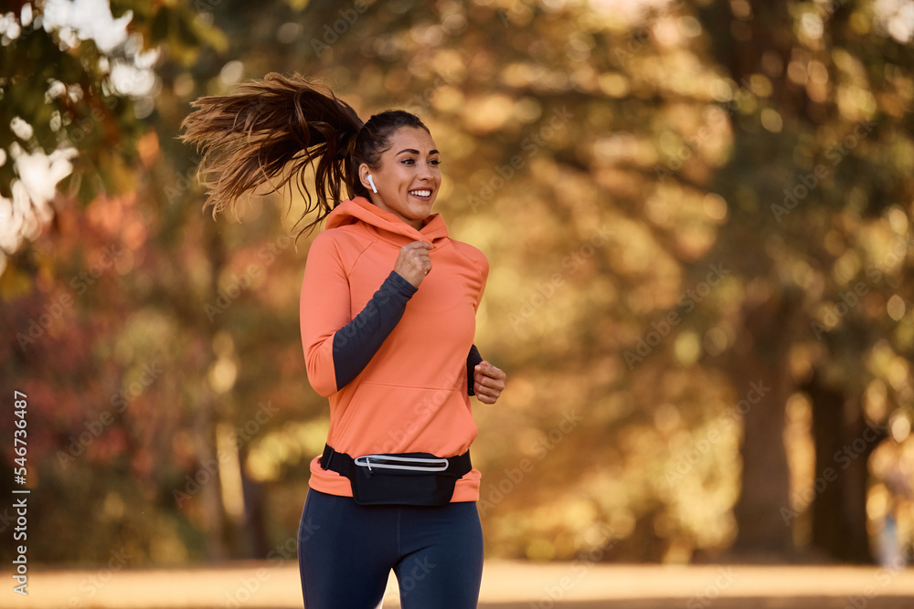 Wall mural Motivated female athlete jogging in park.