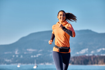 Happy female runner jogging in nature.