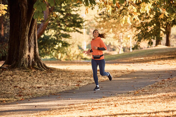 Fototapeta premium Happy sportswoman running during autumn day in nature.