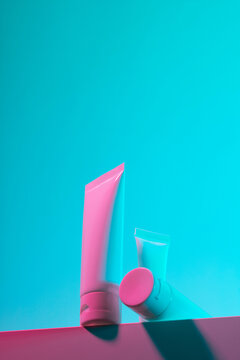 Set of pink and blue hand-cream tubes on pink background in studio