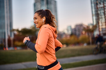Happy female athlete running while exercising outdoors.