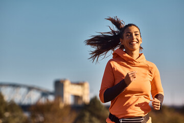 Happy female athlete jogging in nature.